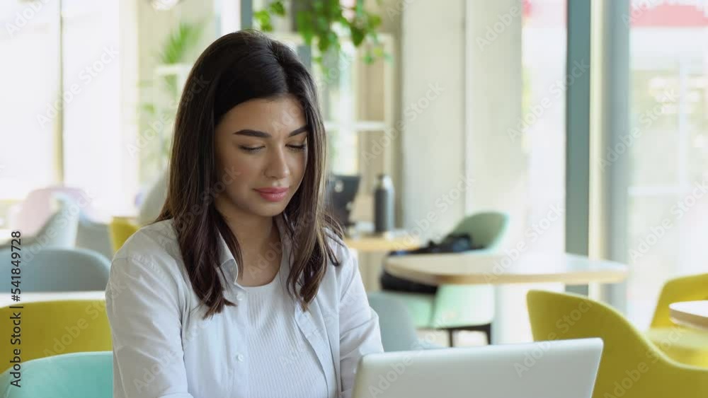Young charming female freelancer using laptop computer for distance job while sitting in modern coffee shop interior Young charming female freelancer using laptop computer for distance job while sitting in modern coffee shop interior