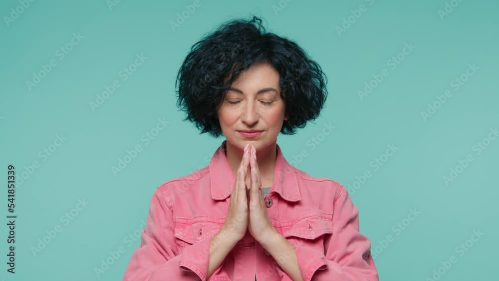 Face portrait of calm mature beauty woman hands gently folded in namaste gesture symbol of salutation and spirituality recognition of the unity and eternal spirituality, slow motion studio 4K footage Face portrait of calm mature beauty woman hands gently folded in namaste gesture symbol of salutation and spirituality recognition of the unity and eternal spirituality, slow motion studio 4K footage
