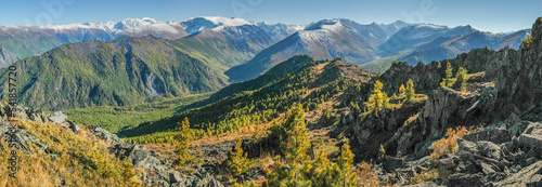 Panoramic mountain view, forested slopes, snow-capped peaks, autumn nature