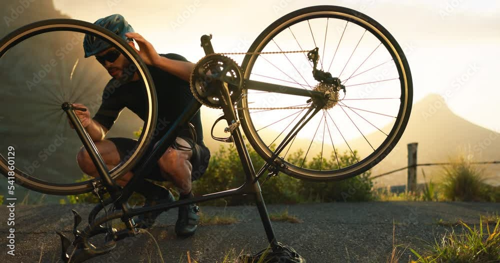 Bicycle, wheel and tyre on road with man athlete fix problem on rim outdoor in sunset. Cyclist, bike or broken in street on training, fitness and exercise ride for sport or prepare for competition