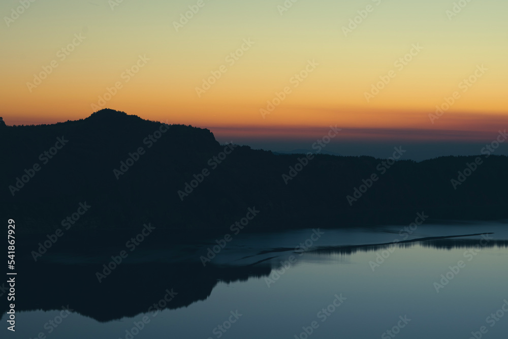 Sunset over Crater Lake National Park in Oregon, with the rim of the Crater in silhouette. 