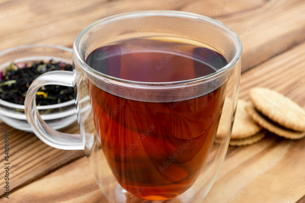 Glass cup of tea with dry tea and cookies on the table. Close up.