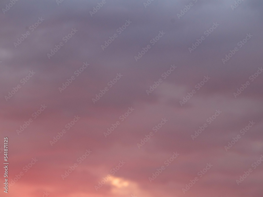 Atmospheric colorful pink sunset with a heavy layer of clouds glowing in the last rays of the sun, full frame, abstract background. Template with plenty space for text.