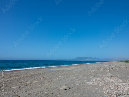 Beautiful and deserted beach on the west coast of Rhodes near Kamiros. Turquoise sea water  blue cloudless sky  pebble beach. Tourism and vacations concept. Space for text.