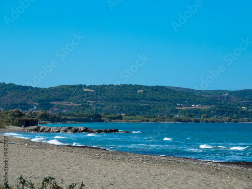 Beautiful and deserted beach on the west coast of Rhodes near Kamiros. Turquoise sea water, blue cloudless sky, pebble beach. Tourism and vacations concept. Space for text.