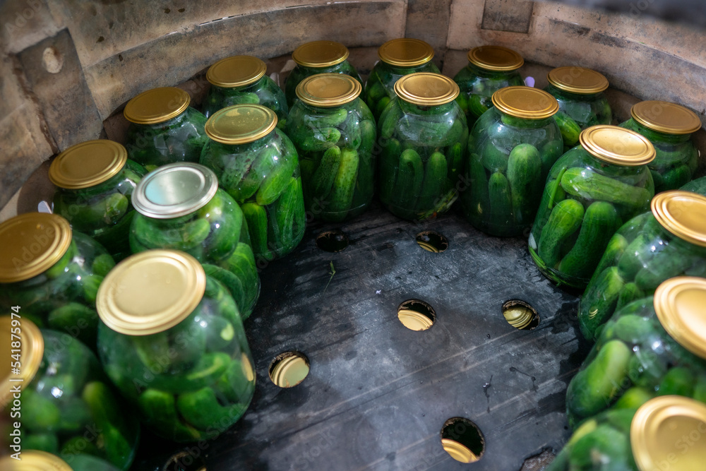 The process of canning vegetables. Cucumbers are packed in jars and