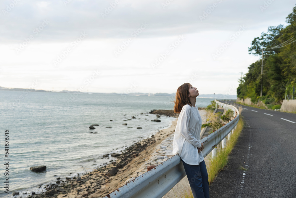 夕暮れの海岸線にいる女性