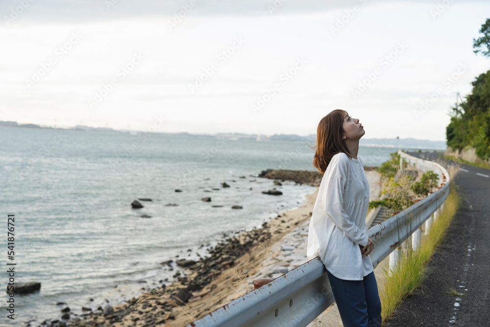 夕暮れの海岸線にいる女性