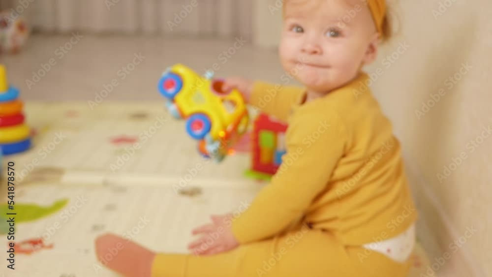 one-year-old girl plays with toys on mat in house, development and learning. in yellow one-year-old girl plays with toys on mat in house, development and learning. in yellow