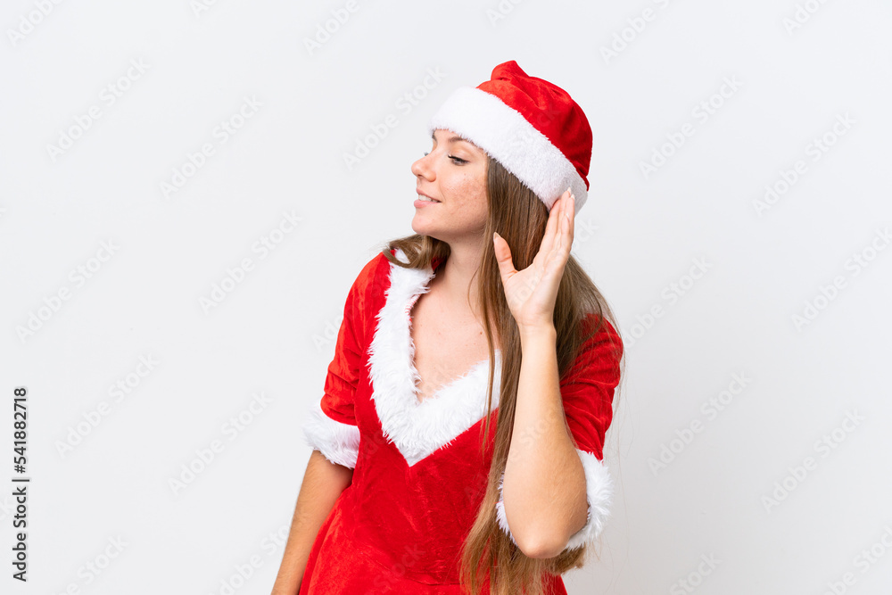 Young caucasian woman dressed as mama noel isolated on white background listening to something by putting hand on the ear Young caucasian woman dressed as mama noel isolated on white background listening to something by putting hand on the ear