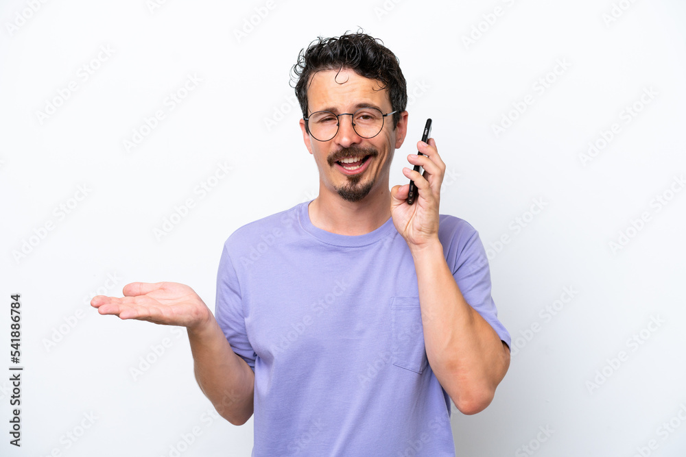 Young man with moustache isolated on white background keeping a conversation with the mobile phone with someone Young man with moustache isolated on white background keeping a conversation with the mobile phone with someone
