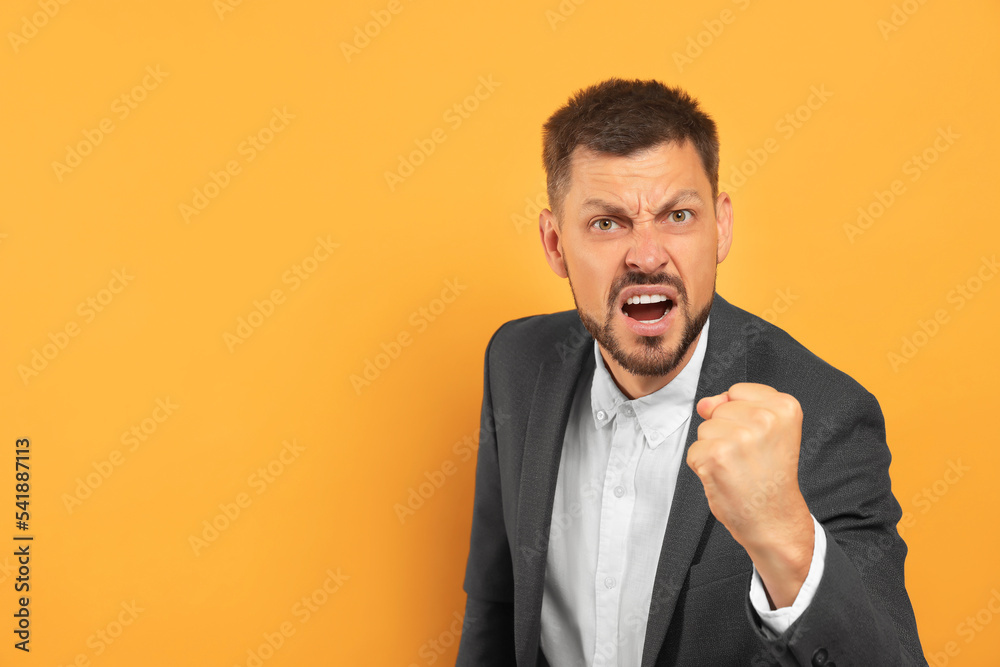Aggressive man on orange background, space for text Aggressive man on orange background, space for text