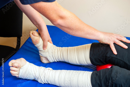 Close-up of male physiotherapist massaging the leg of patient in a physio room.