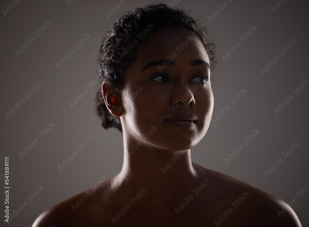 Beauty, skincare and face with a model woman in a dark studio on a gray background for health or wellness. Cosmetics, natural and skin with an attractive young woman posing to promote antiaging care Beauty, skincare and face with a model woman in a dark studio on a gray background for health or wellness. Cosmetics, natural and skin with an attractive young woman posing to promote antiaging care
