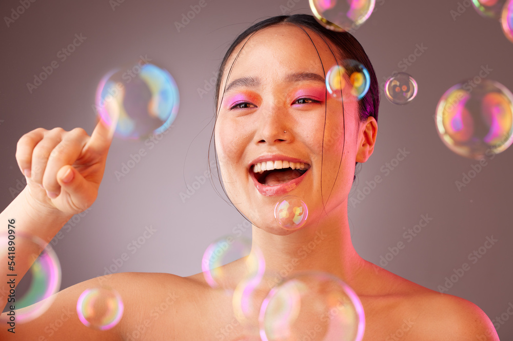 Beauty, bubbles and Asian woman with bright eyeshadow isolated on a studio background. Fun, glamour and colourful cosmetics with a beautiful Chinese woman popping bubbles for a healthy, fresh skin Beauty, bubbles and Asian woman with bright eyeshadow isolated on a studio background. Fun, glamour and colourful cosmetics with a beautiful Chinese woman popping bubbles for a healthy, fresh skin