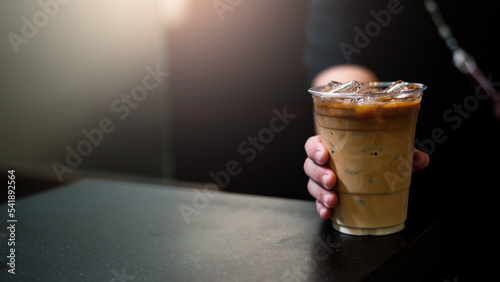 Foto hand holding a take-out iced coffee on black table