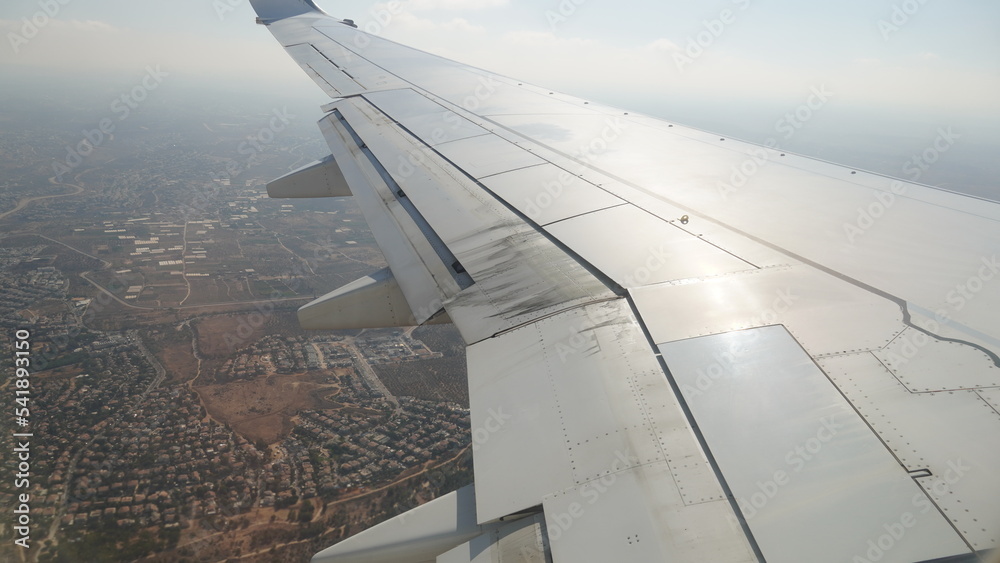 Wing of an airplane flying over Israel, Passenger s view. Looking through the window of a plane on its shining wing