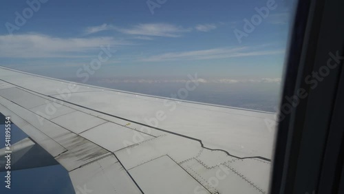 Wing of an airplane, passenger's view. Looking through the window of a plane on its shining wing