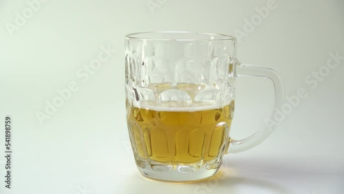 Pouring beer into glass with bubbles close up.  Beer is pouring from the top into the glass forming a foam