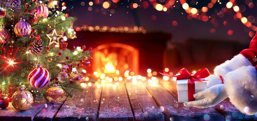 Santa Claus Give Present Under Christmas Tree - Gift Box and Ornament In Interior Home With Abstract Defocused Lights At Night