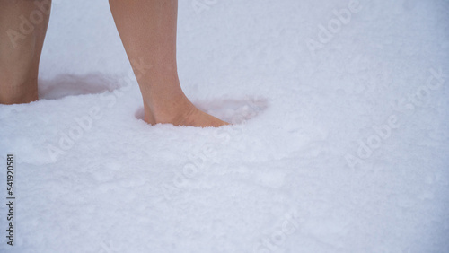 Close-up of a woman walking barefoot in the snow. Boosting immunity with cryotherapy.