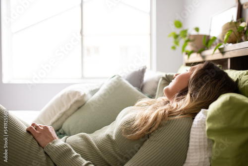 woman  lying on bed while looking at window with green and white pillows photo