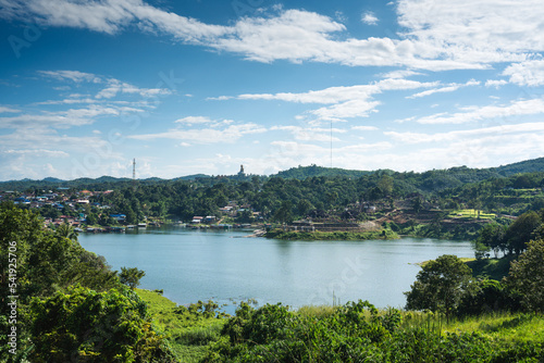 Scenery of Mon village on riverside and big buddha statue on hill in tropical rainforest on dam at Sangkhlaburi