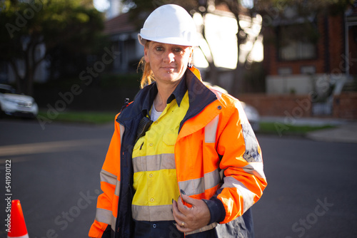 Close up shot of a woman road worker with white helmet and orange jacket with a silver reflector photo