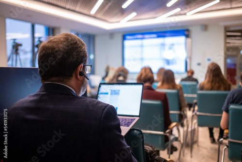 Businessman with laptop taking photos during conference