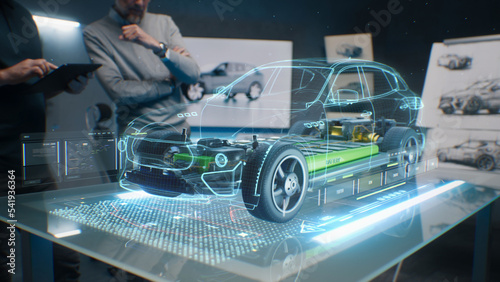 Car design engineers using holographic app in digital tablet. Develop modern innovative high-tech cutting edge eco-friendly electric car with sustainable standards. They test the aerodynamic qualities photo