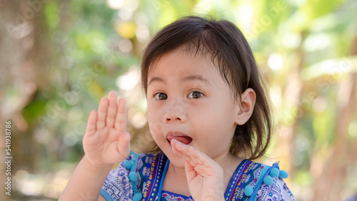 Portrait of positive charming 4 years old cute baby Asian girl, preschooler child showing tongue. Children with funny expressions on her face.