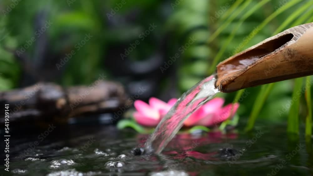 Water flows from bamboo gutter pipes, smoke floats in, pink lotus flowers, blurred green leaf background. Water flows from bamboo gutter pipes, smoke floats in, pink lotus flowers, blurred green leaf background.