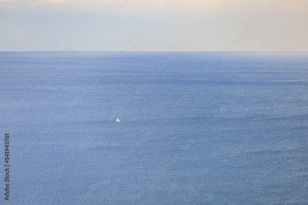 広い穏やかな海と1隻の白い帆のヨット