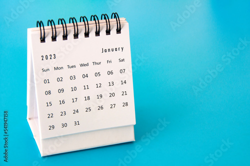 January 2023 white desk calendar on blue background. Calendar concept
