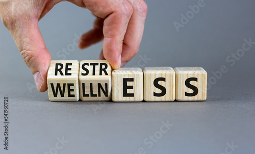 Restress for wellness symbol. Concept words Restress and Wellness on wooden cubes. Businessman hand. Beautiful grey table grey background. Business Restress for wellness concept. Copy space.