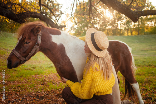 Beautiful portrait, woman and pony, spotted horse, in autumn forest, pleasant colors, background. concept of love, tenderness, friendship. Arms