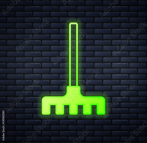 Glowing neon Garden rake icon isolated on brick wall background. Tool for horticulture, agriculture, farming. Ground cultivator. Housekeeping equipment. Vector