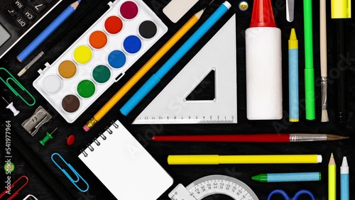 Horizontal composition of colorful school supplies moving upwnwards on blackboard background. School and Education concept. Seamless looping. High quality 4k video.