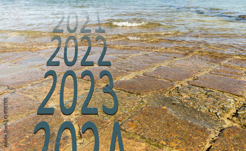 Bonne et heureuse année 2023, élégante carte de voeu montrant la fin de 2022, le passage à 2023 et l'écoulement du temps sur fond de route inondée. Espace pour texte photo