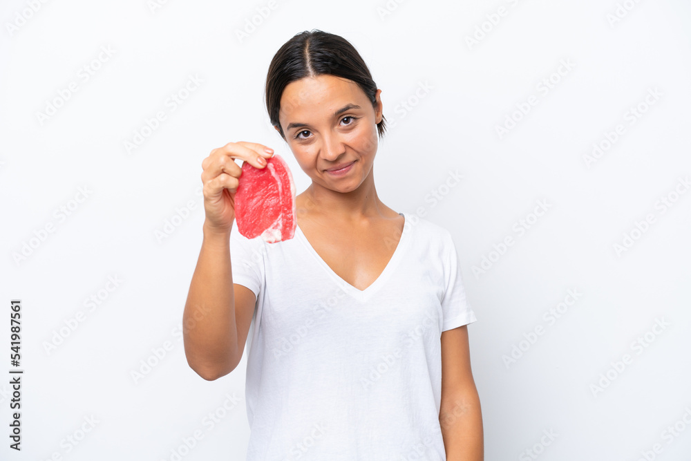 Young hispanic woman holding a piece of meat isolated on white background with happy expression Young hispanic woman holding a piece of meat isolated on white background with happy expression