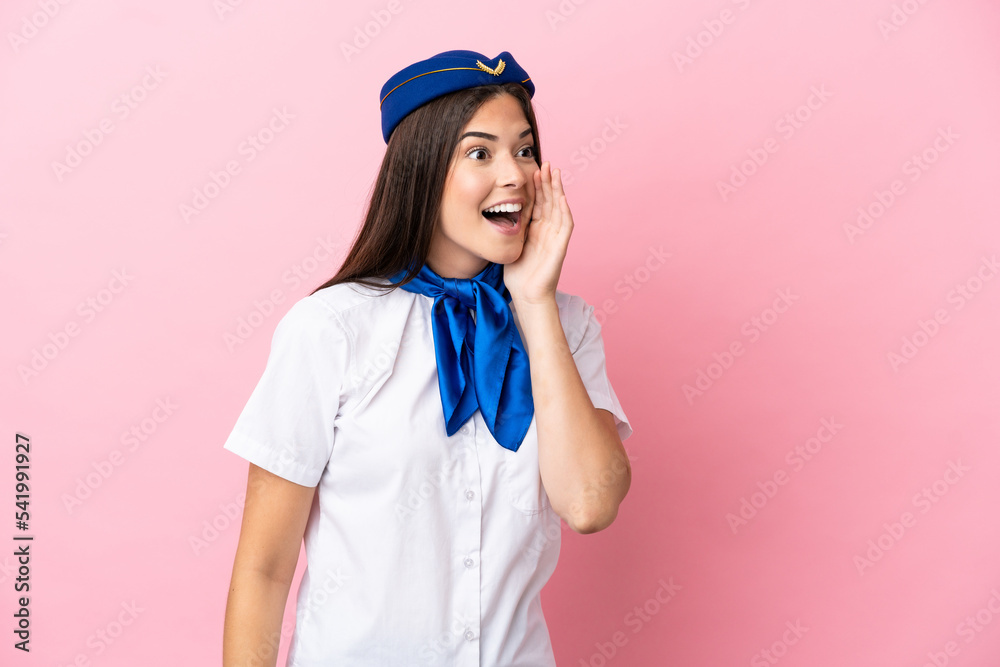 Airplane stewardess Brazilian woman isolated on pink background shouting with mouth wide open to the lateral Airplane stewardess Brazilian woman isolated on pink background shouting with mouth wide open to the lateral
