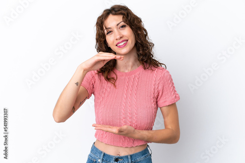 Young woman with curly hair isolated on white background holding copyspace imaginary on the palm to insert an ad