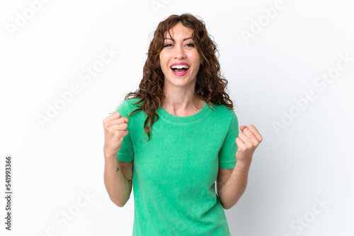 Young woman with curly hair isolated on white background celebrating a victory in winner position