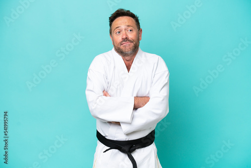 Middle age caucasian man isolated on blue background making doubts gesture while lifting the shoulders