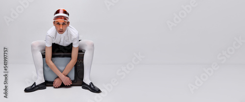 Portrait of stylish young man, boy posing in white tights on retro TV isolated over grey background. Flyer. Fashion show
