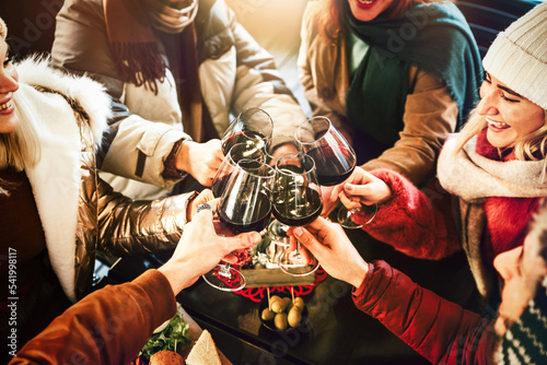 Foto Happy friends group wearing winter clothes celebrating with red wine glasses at