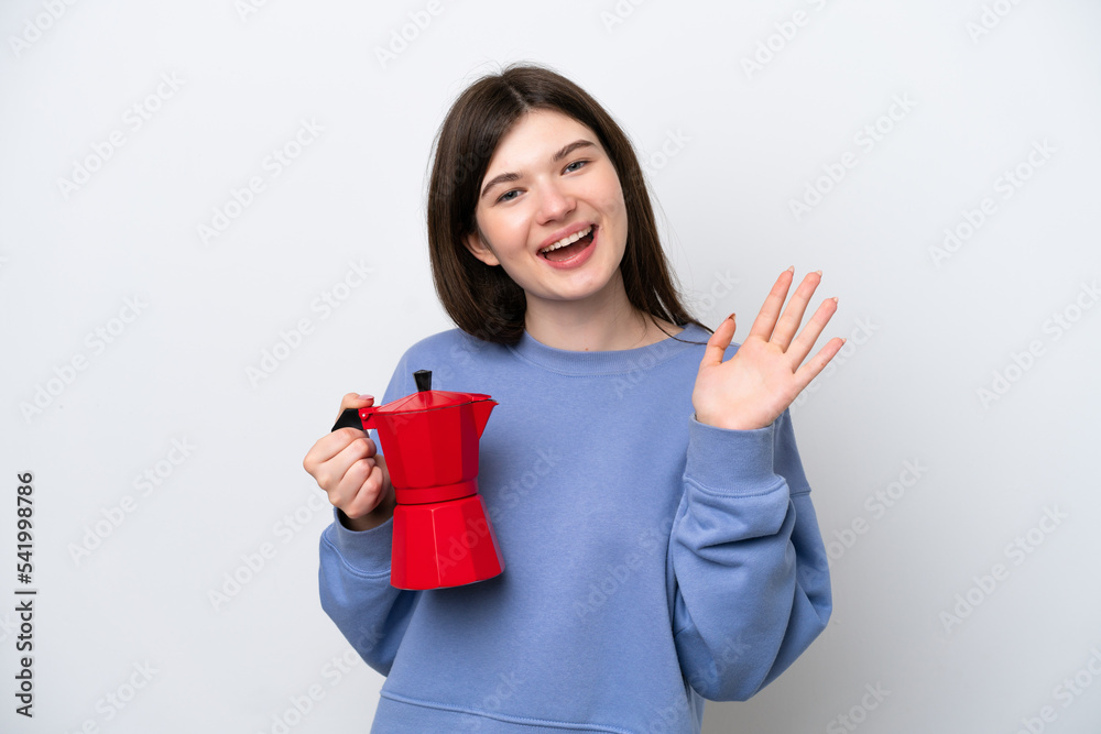Young Russian woman holding coffee pot isolated on white background saluting with hand with happy expression Young Russian woman holding coffee pot isolated on white background saluting with hand with happy expression