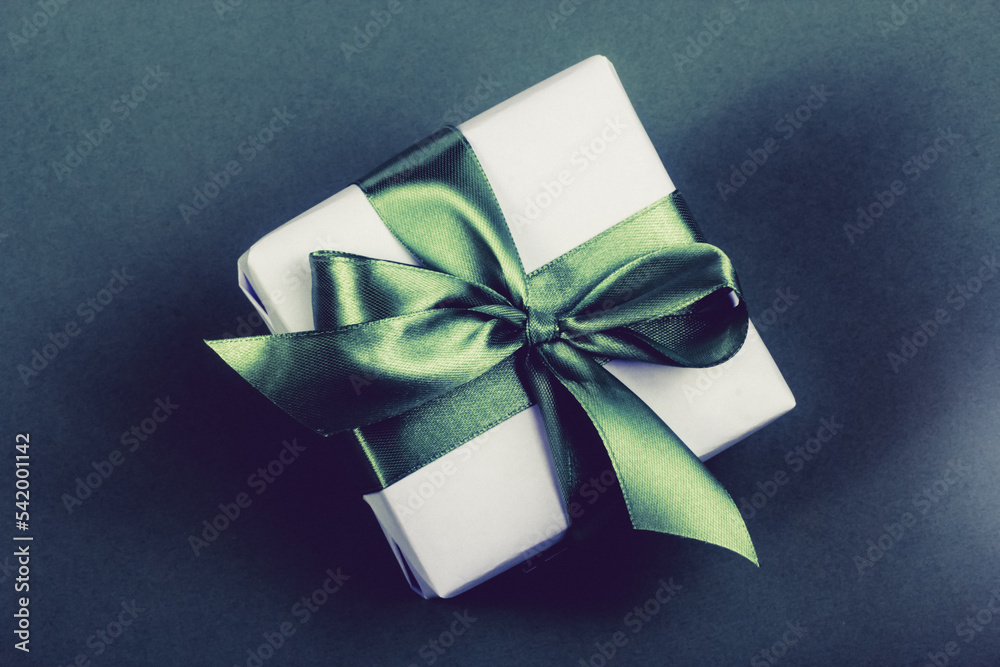 Gift box with green bow on dark background