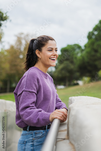 pretty woman laughing on a park bridge in a purple blouse