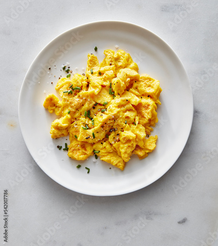 Scrambled eggs on white plate with chives